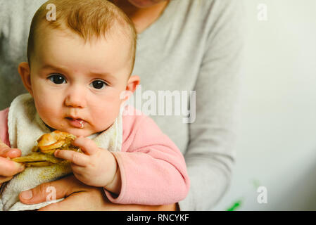 4 mois du grignotage une cuisse de poulet, sa première dégustation des aliments à l'aide de la méthode de sevrage led Bébé BLW. Banque D'Images