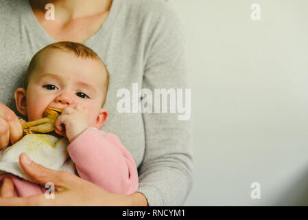 Bébé âgé de 5 mois de manger une cuisse de poulet à l'aide de l'enfant conduit le sevrage BLW méthode. Banque D'Images