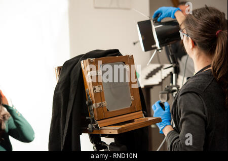 Femme photographe définit les ligths pour studio de tournage. Appareil photo grand format dans l'avant-plan. Banque D'Images