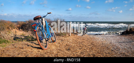 Prêt de vélos par l'entrée de la plage sur l'île de Hiddensee, mer Baltique, du nord de l'Allemagne. Jour lumineux avec ciel bleu en automne ou en hiver. Photo panoramique. Banque D'Images