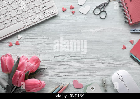 Télévision printemps pondent avec clavier, souris, des tulipes roses, papeterie, cartes de vœux, des coeurs décoratifs et copy-espace au milieu. Préparation d'une b Banque D'Images