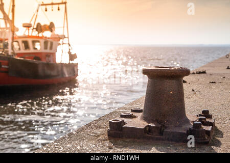 Bollard sur quai avec bateau de pêche en arrière-plan Banque D'Images