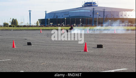 Les compétitions de karting, karting ci conduit un kart dans le contexte d'un immeuble moderne, beaucoup de fumée, gagnant, racer Banque D'Images