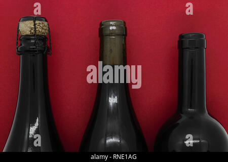 Fermé par des bouchons de champagne et vin bouteilles noir sur fond rouge Banque D'Images