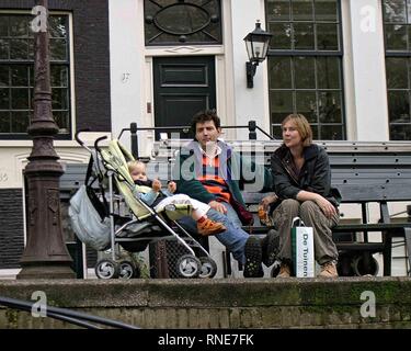 Amsterdam, Pays-Bas. 9 octobre, 2005. Un jeune couple se reposer sur un banc avec leur enfant dans une poussette sur les rives d'un canal à Amsterdam, aux Pays-Bas. Credit : Arnold Drapkin/ZUMA/Alamy Fil Live News Banque D'Images