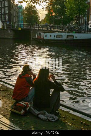 Amsterdam, Pays-Bas. 9 octobre, 2005. Deux jeunes femmes s'asseoir par un canal à Amsterdam, aux Pays-Bas. Credit : Arnold Drapkin/ZUMA/Alamy Fil Live News Banque D'Images