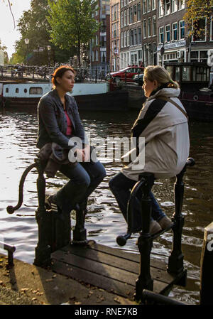 Amsterdam, Pays-Bas. 9 octobre, 2005. Deux jeunes femmes s'asseoir par un canal à Amsterdam, aux Pays-Bas. Credit : Arnold Drapkin/ZUMA/Alamy Fil Live News Banque D'Images