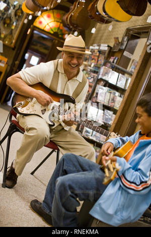 Grand-père et petit-fils en magasin à jouer de la guitare Banque D'Images