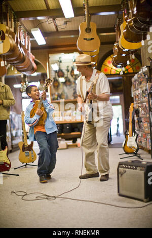 Grand-père et petit-fils en magasin à jouer de la guitare Banque D'Images