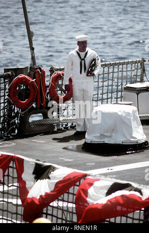 1982 - Un homme d'équipage se prépare à lever le drapeau pendant la mise en service des cérémonies pour la frégate lance-missiles USS LEWIS B. PULLER (FFG-23). Banque D'Images