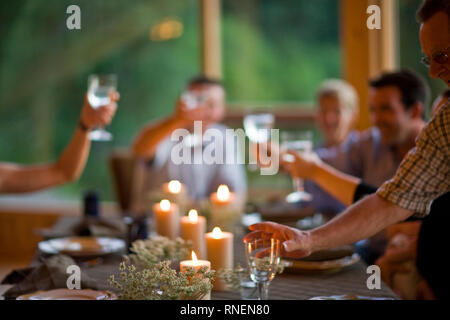 Famille faire un toast at dinner table Banque D'Images