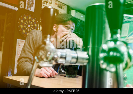 Bon gars fume cigarette irlandaise et boire de la bière dans un pub pendant le jour de la St Patrick (filtre représentent drapeau irlandais) Banque D'Images