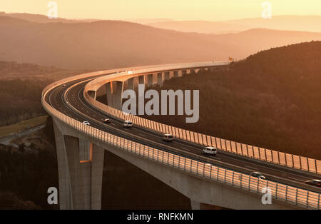 Les voitures qui circulent sur une route viaduc à beau coucher du soleil Banque D'Images