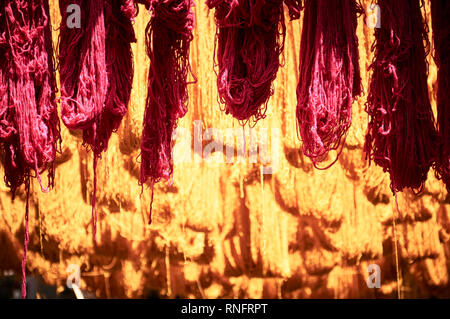 Des paquets de chaîne de laine accroché les poteaux de bambou frais généraux à sécher au soleil dans le district de teinture les rues de Marrakech. Banque D'Images