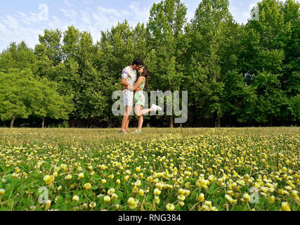 Heureux couple d'amoureux qui s'embrassent dans un champ plein de fleurs jaunes. Banque D'Images
