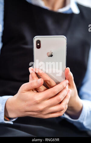 PARIS, FRANCE - Oct 2, 2018 : business woman holding silver New Apple iPhone téléphone smartphone Max Xs à partir de tous les ordinateurs Apple avec écran OLED home apps sur Banque D'Images