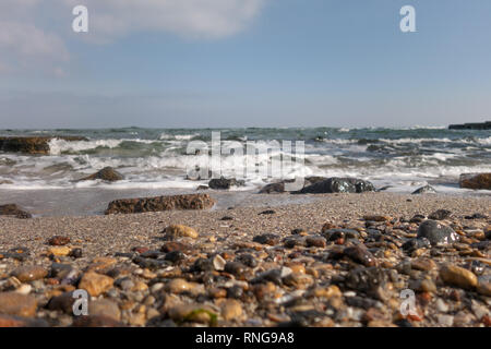 Mer et de la plage et de la mer sur une journée de printemps ensoleillée. Vagues sur la plage de sable et rochers du littoral. Focus sélectif. Banque D'Images