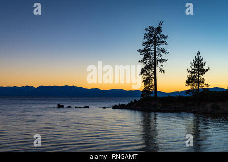 Ciel clair au coucher du soleil au port de sable avec l'eau calme, les silhouettes des arbres, et les montagnes en arrière-plan, le lac Tahoe, Carson City, Nevada Banque D'Images