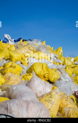 Jeter des sacs en plastique jaune et blanc rempli d'amiante fibres à un chantier de recyclage Banque D'Images