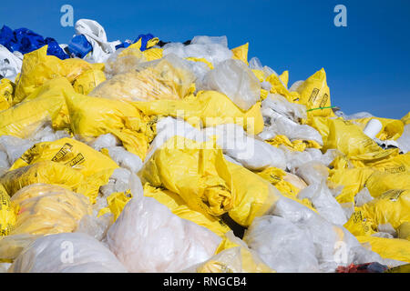 Jeter des sacs en plastique jaune et blanc rempli d'amiante fibres à un chantier de recyclage Banque D'Images