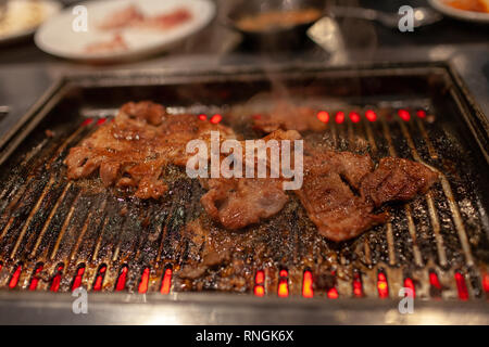 Korean style barbecue avec le boeuf mariné juteux sur la plaque chaude avec de la fumée de cuisson émettant. Banque D'Images