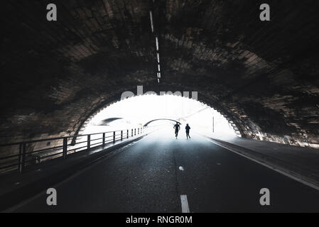 Route à travers des vieux tunnel et silhouette de personnes courir vers la lumière. Voie à suivre. Ombre et lumière. Un passage à Paris. Banque D'Images