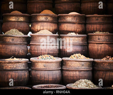 Plusieurs d'ornement cuivre bols urne contenant des herbes séchées et des fleurs dans un décrochage dans le souk de la médina de Marrakech. Banque D'Images