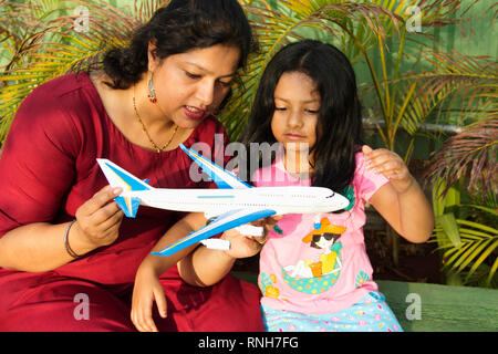 Mère montrant sa fille un toy airplane alors que petite fille en l'observant attentivement, Pune Banque D'Images