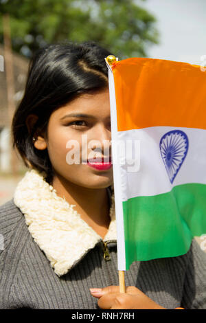 Close-up of young Indian girl holding drapeau national indien couvrant la moitié de son visage, Pune Banque D'Images