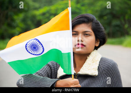 Close-up of young Indian girl holding drapeau national indien et à le regarder avec fierté, Pune Banque D'Images