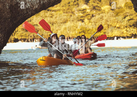 Groupe d'amis heureux des balades en kayaks sous de gros rochers dans la mer. Kayak ou canot travel photo avec un groupe d'autochtones Banque D'Images