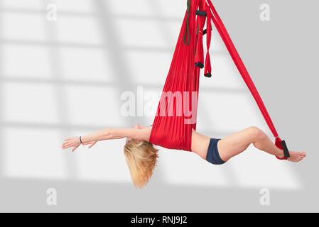 Fly yoga. La fille est engagée dans le yoga de l'antenne dans un hamac. La formation de remise en forme Salle de sport blanc loft classe. Banque D'Images