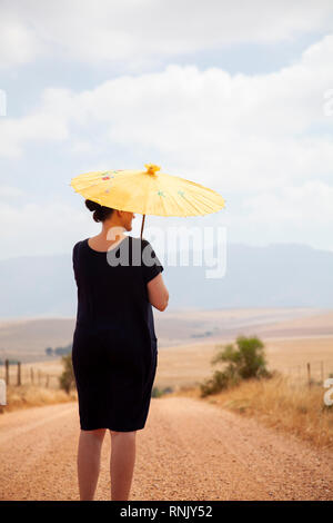 Mature Woman in Black Dress with Umbrella in Countryside Banque D'Images