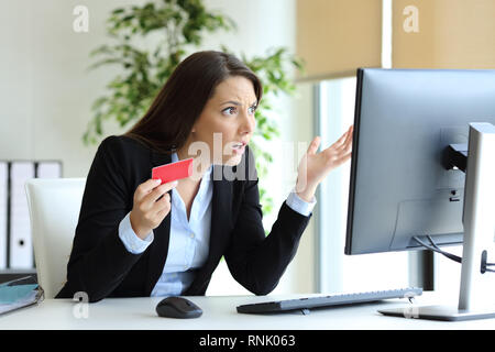 Employé de bureau confus essayant de payer en ligne par carte de crédit sur un ordinateur de bureau Banque D'Images
