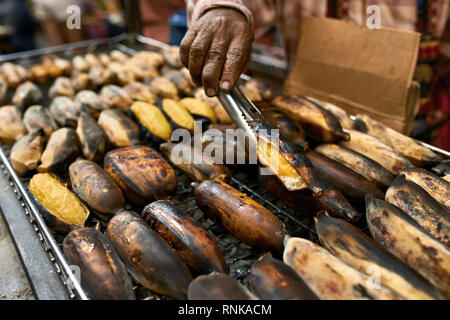 Grand barbecue avec bananes frites sur le marché de rue d'Asie à Bangkok en Thaïlande. Vendeur est maintenant l'un d'entre eux avec l'aide de pinces. Libre de horizont Banque D'Images