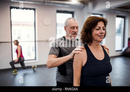 A senior woman in gym faire de l'exercice avec un entraîneur personnel. Banque D'Images