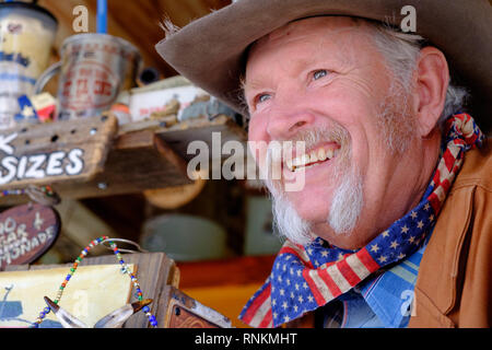 Staycation. Cowboy texan souriant avec chapeau de cowboy, écharpe et moustache en fer à cheval blanc au stand du marché de la soda du Far West. Marché des journées d'échange. Banque D'Images