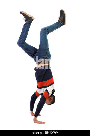Vue latérale d'un homme debout sur ses mains. Guy élégant dans un chandail et un jean fait une vue arrière. L'ATR de personne. Isolated over white backgrou Banque D'Images