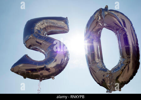 Ballons d'argent pour un 50e anniversaire parmi les nuages flottants Banque D'Images