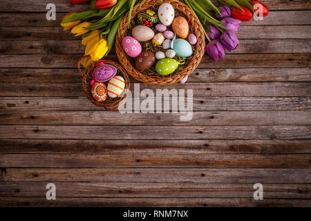 Les oeufs de Pâques colorés et de la direction générale de fleurs sur fond de bois Banque D'Images