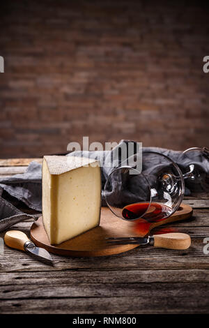 Coin de fromage avec un verre de vin rouge sur fond de bois vintage Banque D'Images