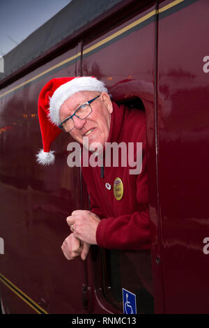 Royaume-uni, Angleterre, dans le Lancashire, Rawtenstall, East Lancashire Railway Station, Santa's Helper, Roger bénévoles Stansfield de Todmorden dans santa hat leaning Banque D'Images