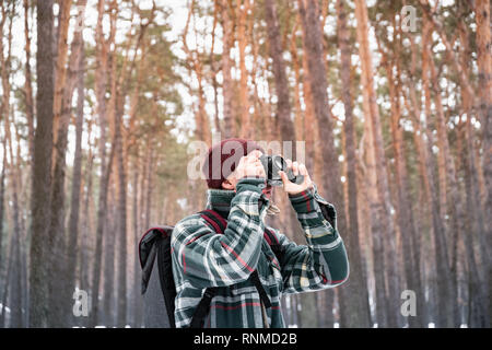 Homme randonnée en hiver en forêt photo. L'homme en chemise à carreaux en hiver belle Snowy Woods utilise de vieux film appareil Banque D'Images