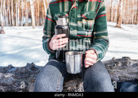 Boisson chaude couler hors de thermos dans un camping. Personne dans une forêt d'hiver au cours d'une randonnée voyage aller au chaud Banque D'Images