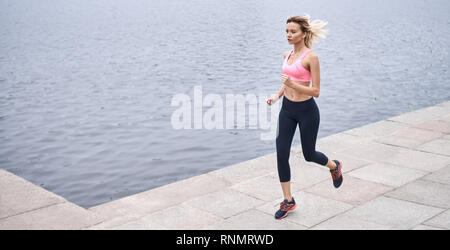 Sérieux au sujet de rester en forme. Vue de dessus de jeune femme en vêtements de sport jogging lors de l'exercice en plein air Banque D'Images