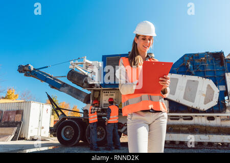 Ingénieur civil femme avec presse-papiers en face de concasseur Banque D'Images