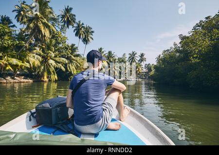 Les jeunes voyageurs touristiques sur bateau contre lagoon du lac au Sri Lanka. Banque D'Images