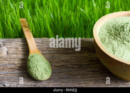 Les jeunes de l'orge et de la spiruline chlorella sur planche de bois et d'herbe verte Banque D'Images