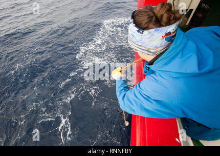 Un chercheur tombe un seau par-dessus bord afin de prélever des échantillons d'eau sur un navire de recherche effectuer une croisière océanographique scientifique dans l'Atlantique Sud Banque D'Images