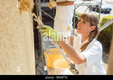 Femme peintre peindre un mur avec de la peinture jaune Banque D'Images